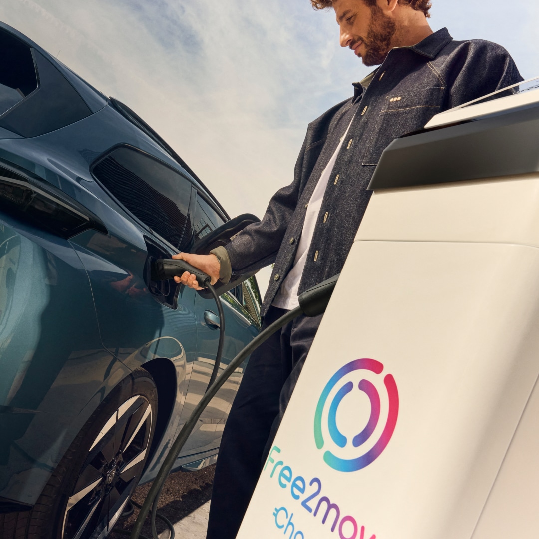 Un homme recharge une PEUGEOT E-308 SW à une borne de recharge