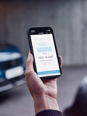 Femme avec smartphone devant le PEUGEOT E-3008 Dual Motor